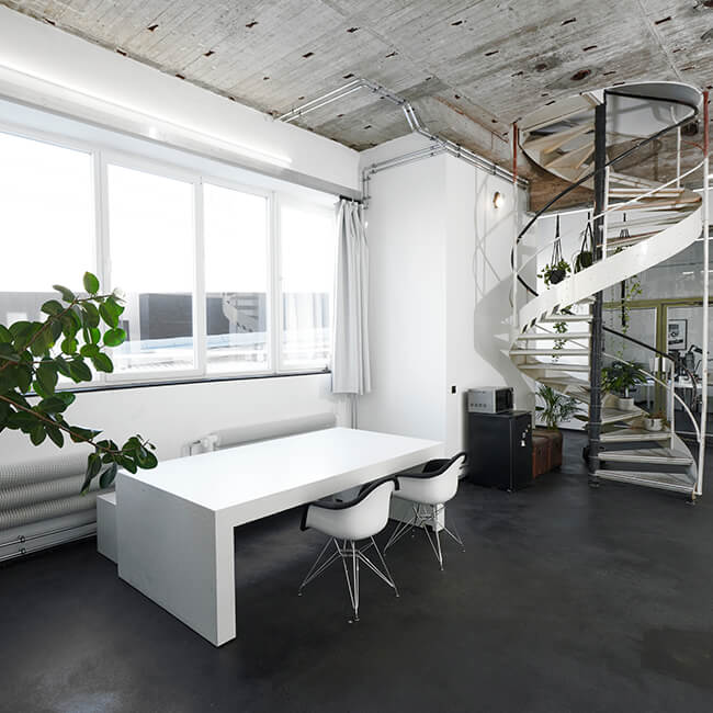 Loungebereich bei raw studios., einem Mietstudio in Berlin, mit großen Fenstern, Zimmerpflanzen und Wendeltreppe