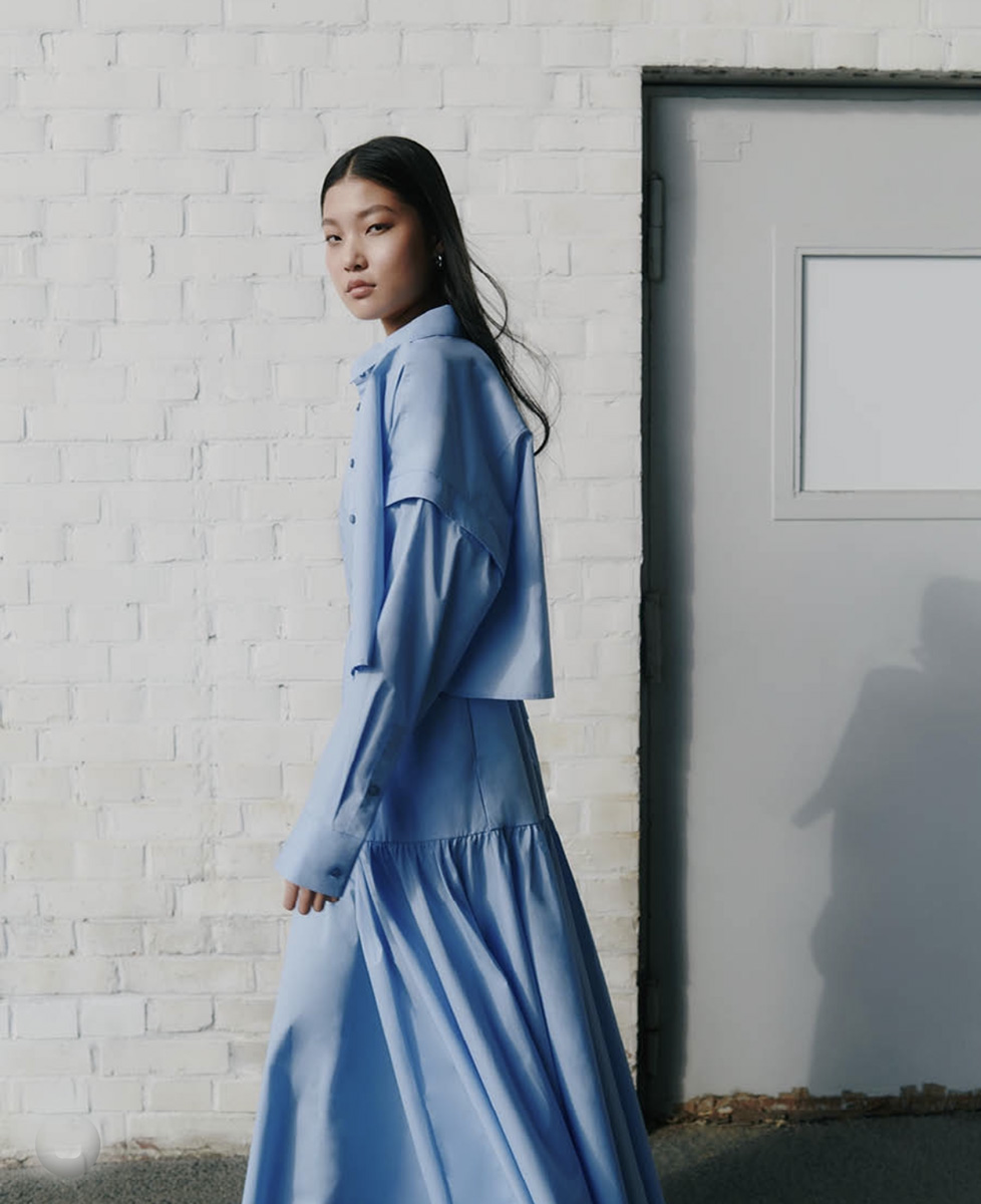 An Asian model posing in blue spring dress outside of raw studios. for their SS24 campaign