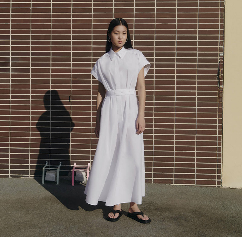 An Asian model posing in white spring dress outside of raw studios. for their SS24 campaign