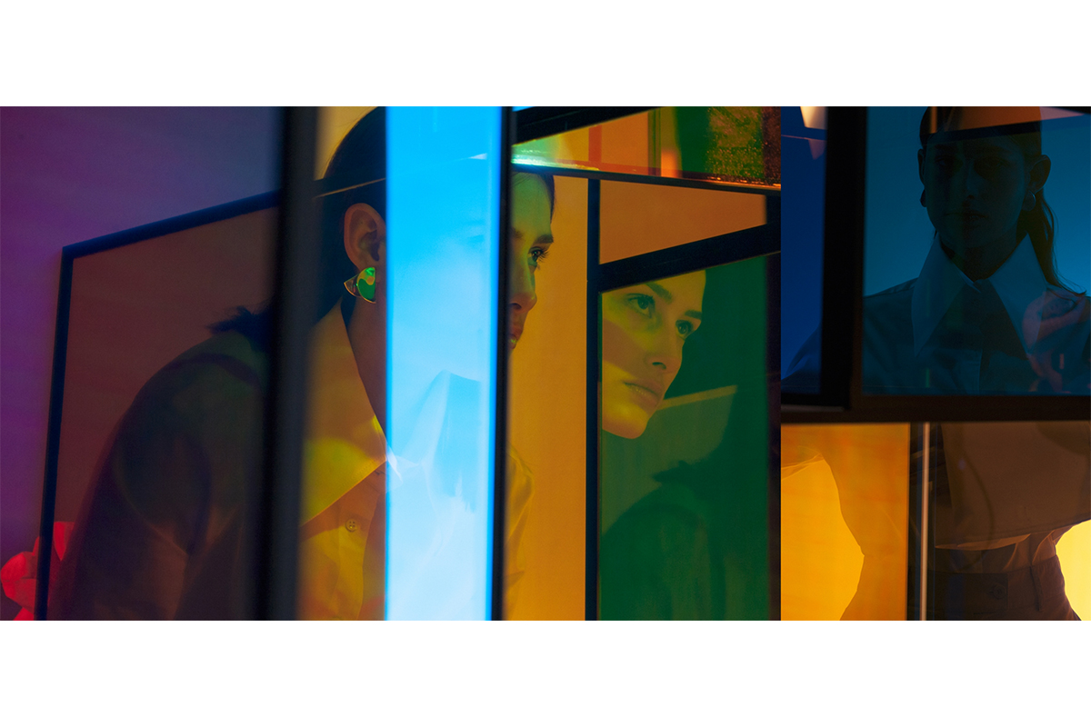 Female model photographed through colorful dichroic glass panels, creating a fragmented, kaleidoscopic portrait. Art installation by Berlin artist Camilla Richter