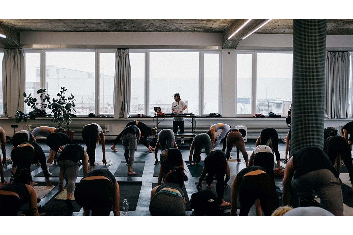 A group of people practicing yoga with a DJ performing in front of them, hosted by BOOM BäNG NAMASTE (BBN)