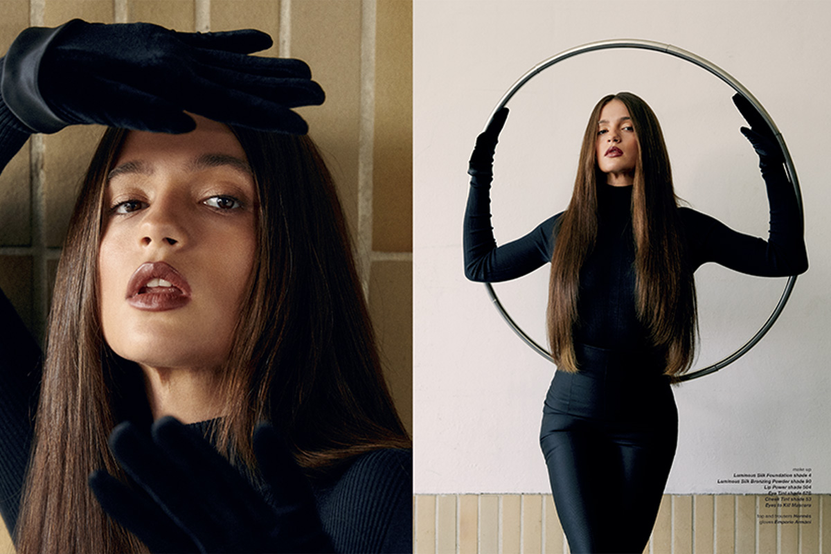 Lisa-Marie Koroll in a striking editorial pose indoors. One image frames her face with a black gloved hand, while another shows her standing with a metal hoop, emphasizing her long, straight hair and sleek black outfit.