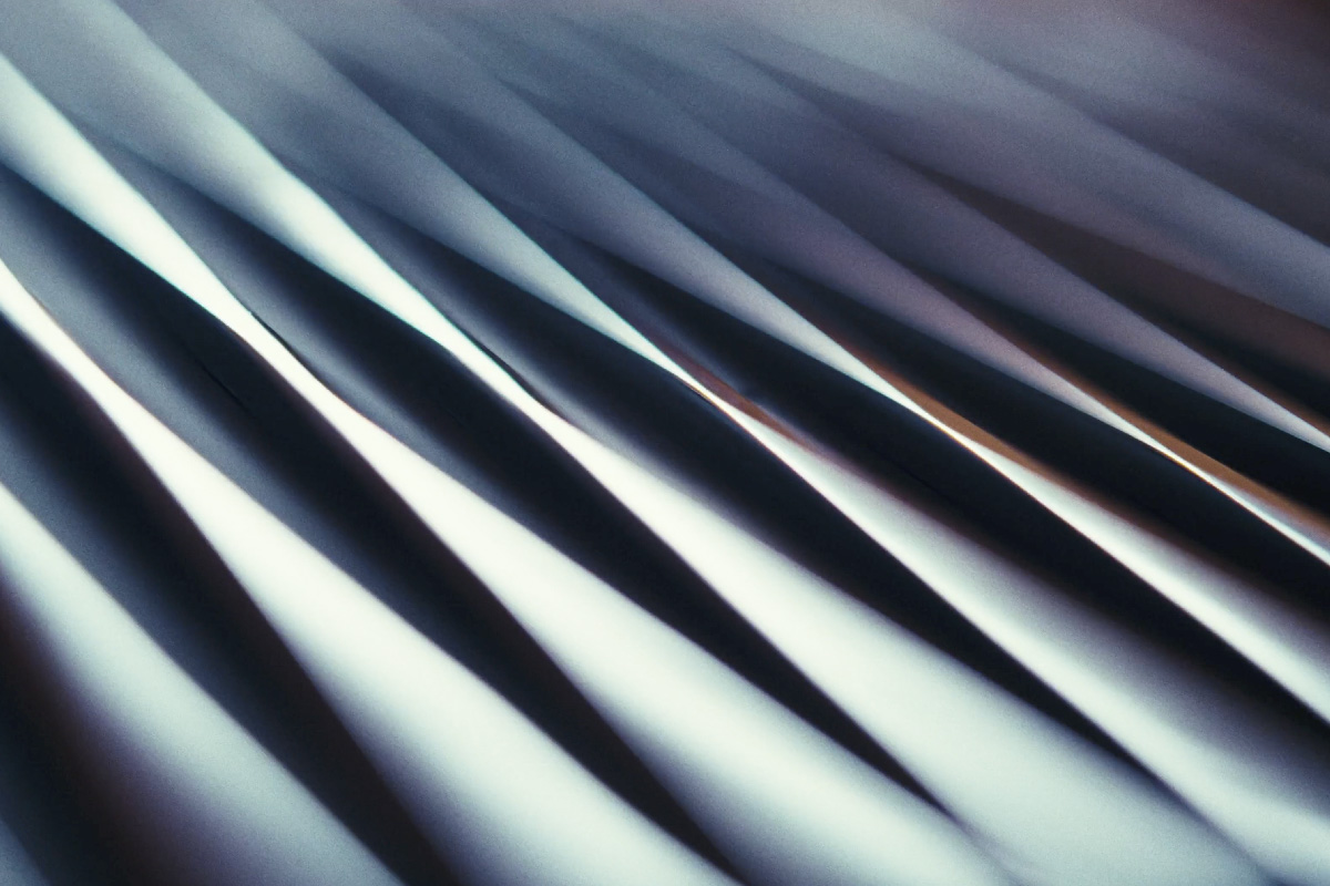 Abstract close-up of undulating fabric or material with sharp, contrasting light and shadow patterns.