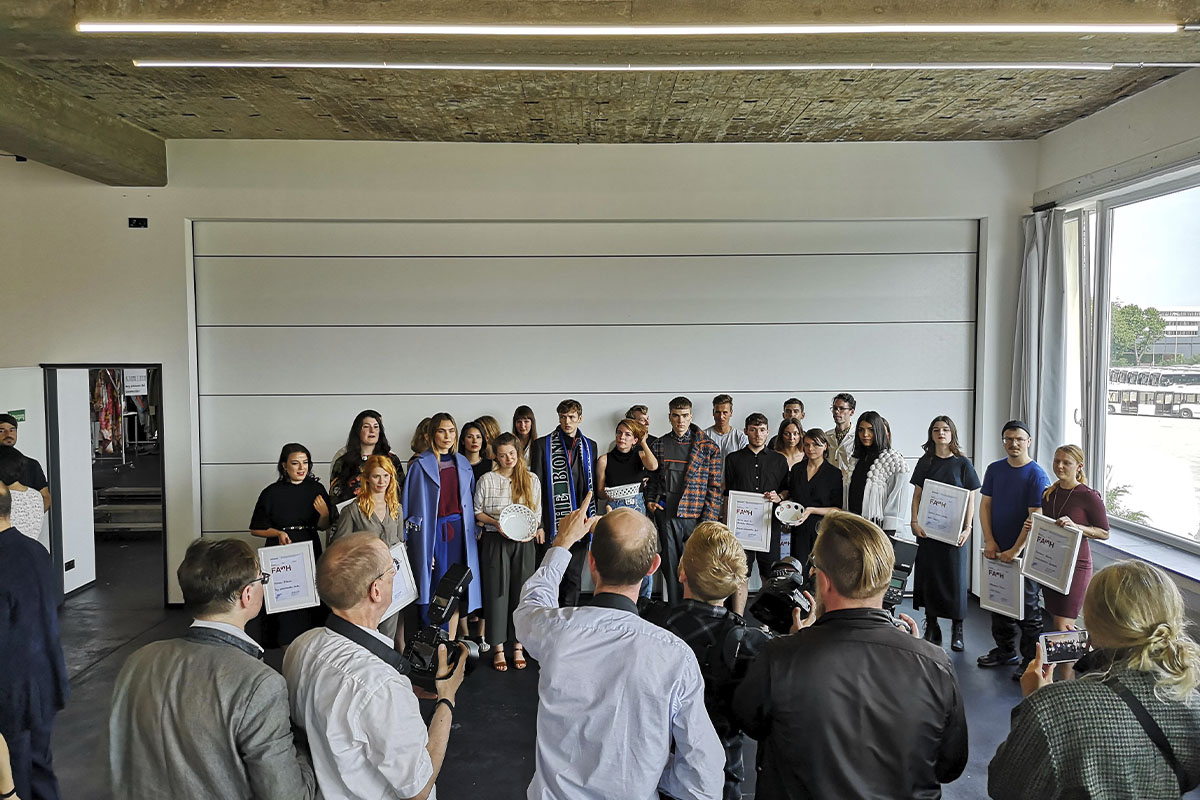 A group of fashion designers and models pose with their awards at raw studios., as photographers capture the celebratory moment.