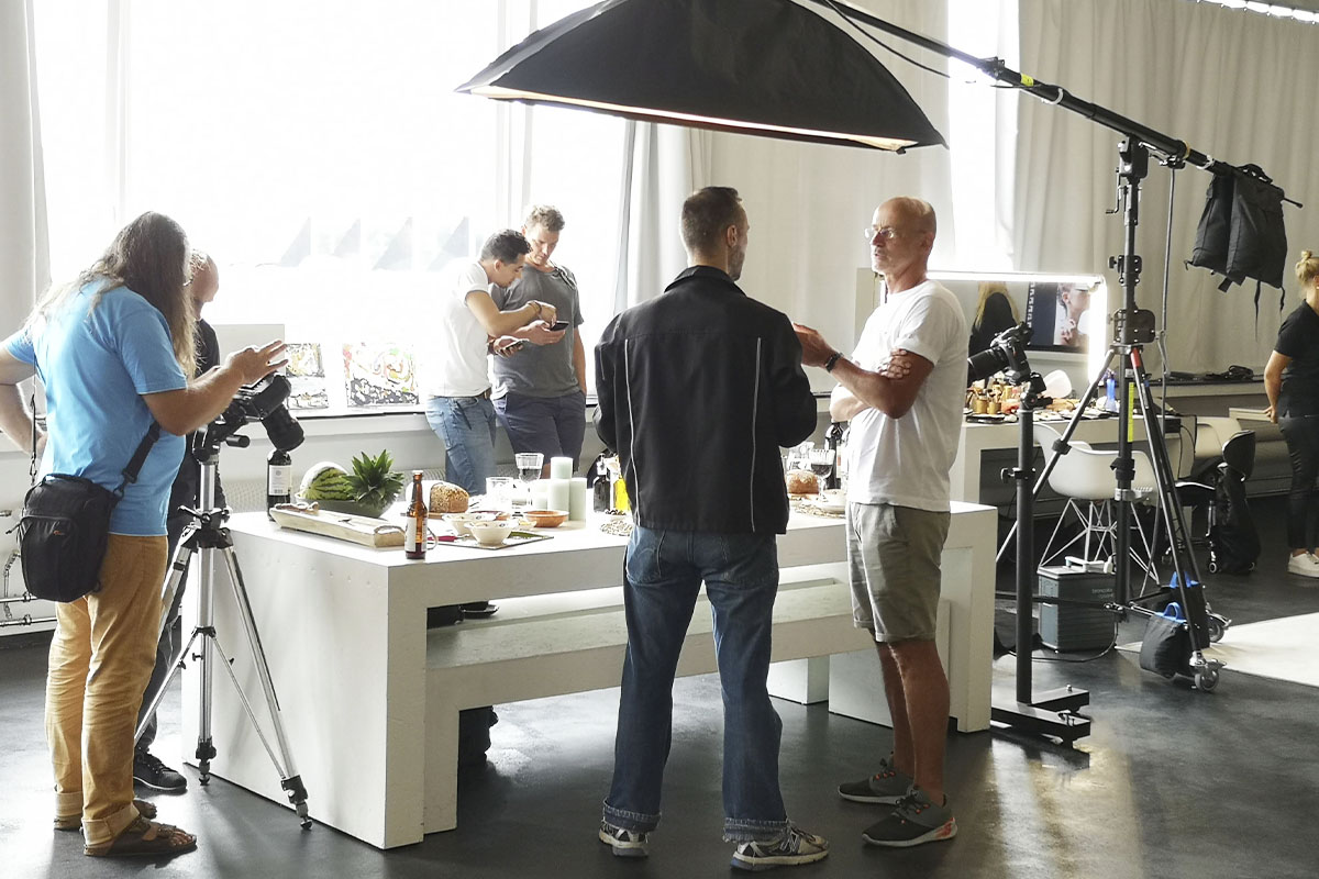 A behind-the-scenes moment from the Fuji Road Show at raw studios., where visitors can test Fujifilm products by capturing sample images of a beautifully arranged table with food and drinks, while engaging with staff for questions and guidance.