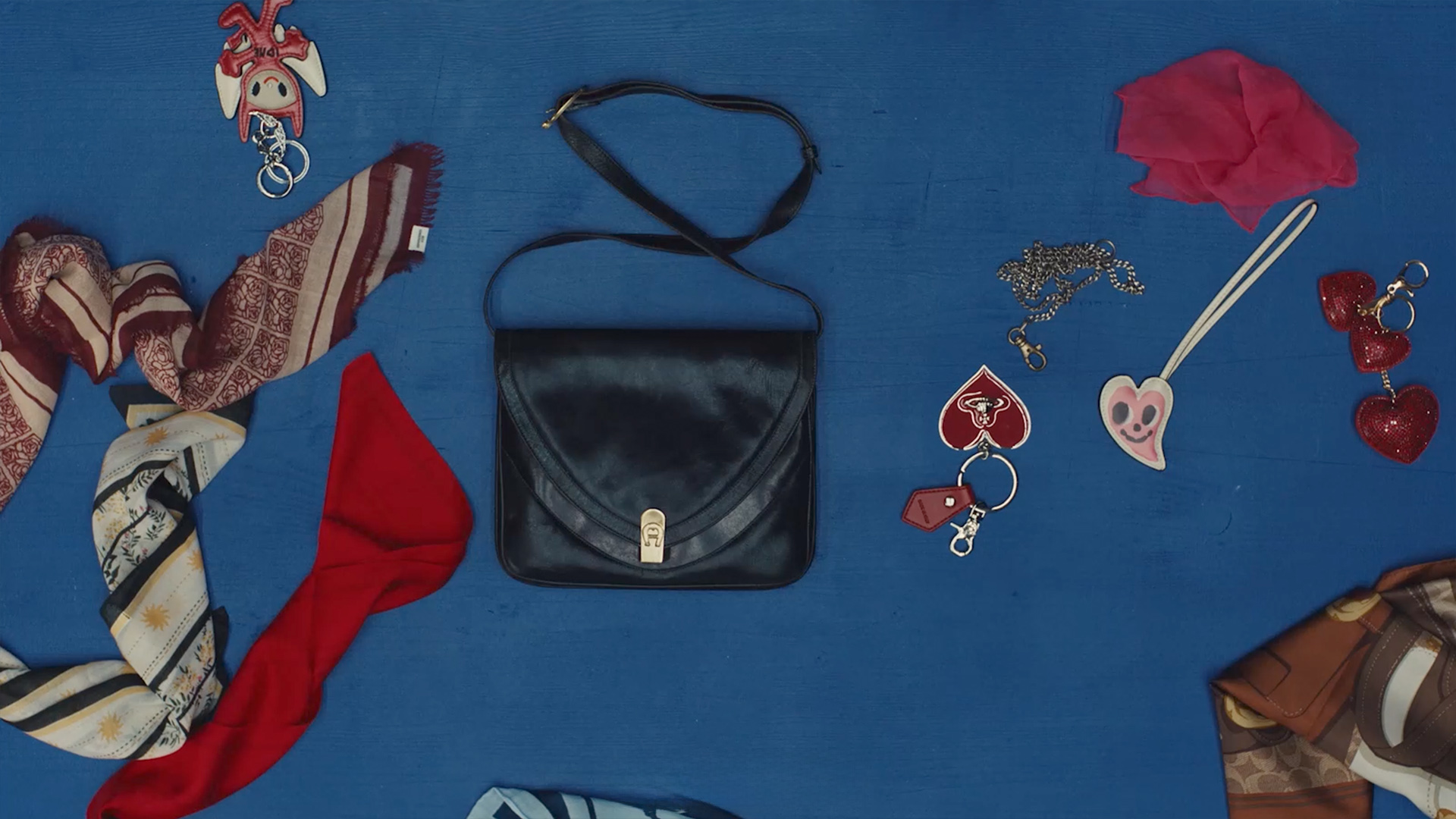 Flat lay of vintage leather bag and accessories on blue table for Zalando Closet Care Episode 3, shot at raw studios. Berlin rental studio with creative set design.