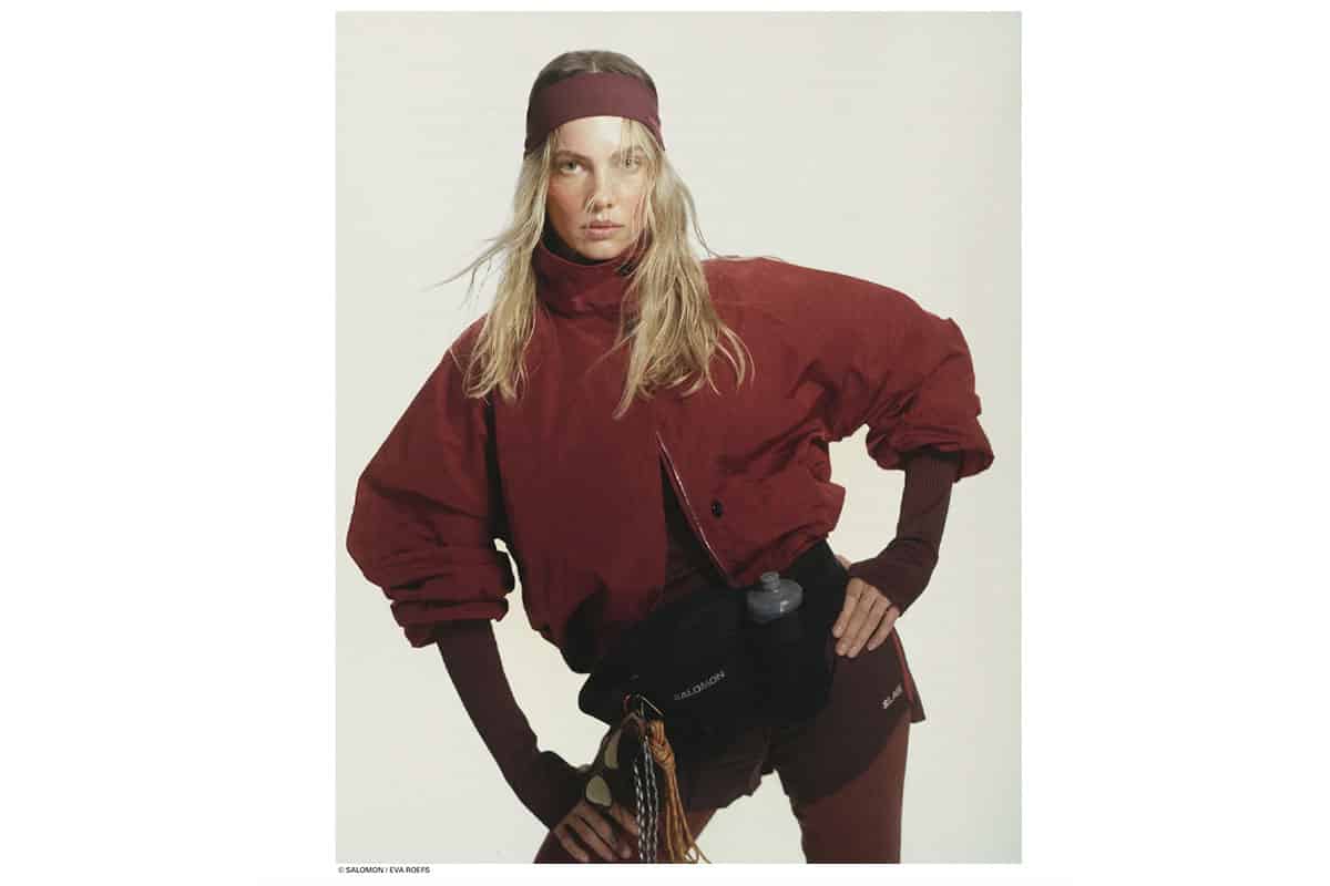 Editorial portrait from the Salomon x Highsnobiety production at raw studios., a creative rental space in Berlin, showing a female athlete in a burgundy jacket, headband, and performance shorts.